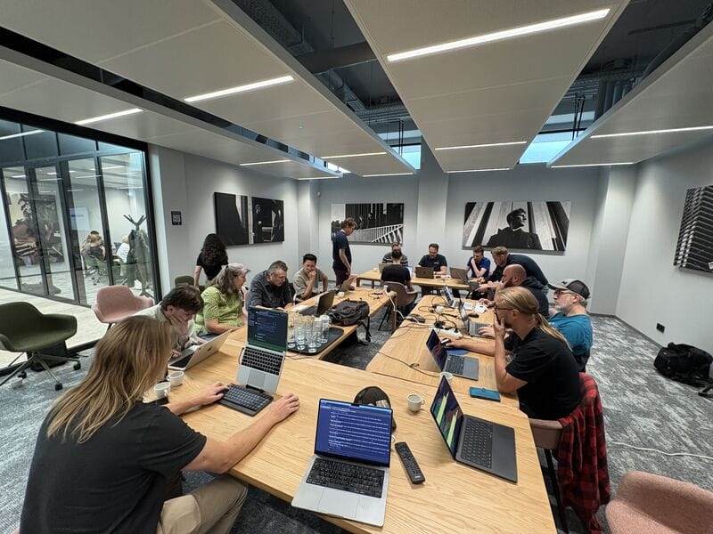 Developers working on laptops around long tables at the Mage-OS hackathon in Zwolle, September 2026